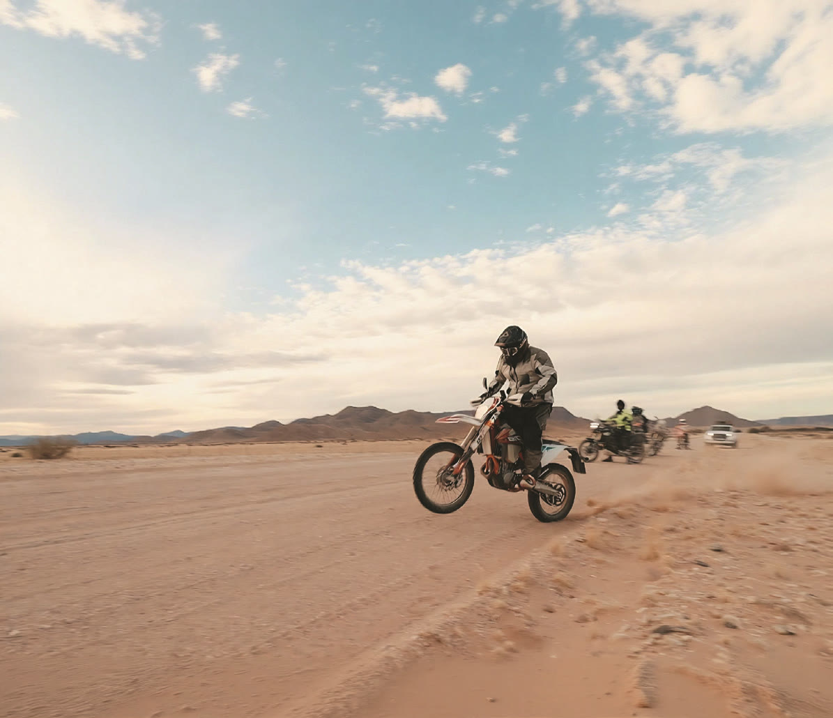 Motorcycle rider kicking up sand on a Namibian desert road